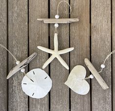 three beach themed ornaments are hanging on a wooden deck with shells and seashells