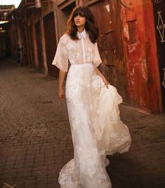 a woman in a white dress is walking down the street