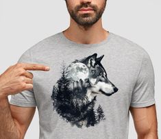 "Introducing our \"Wilderness Guardian\" T-shirt - where the majestic silhouette of a wolf merges seamlessly with the rugged beauty of forested mountains and the mystique of the moon. This tee is a captivating homage to the untamed spirit of the wilderness and the guardianship of nature. Printed on high-quality fabric with meticulous attention to detail, this tee is not just clothing; it's a wearable ode to the wilderness. The double-exposed image of the wolf, forested mountains, and moon creates a mesmerizing fusion of elements, evoking a sense of mystery, strength, and harmony with nature. Whether you're an outdoor enthusiast, a nature lover, or someone who appreciates the raw beauty of the wilderness, the \"Wilderness Guardian\" T-shirt is a must-have addition to your wardrobe. Wear it Wolf Design Graphic Tee With Short Sleeves, Graphic Tee With Wolf Design, Short Sleeve, Graphic Tee With Wolf Design Short Sleeve, Forested Mountains, Double Exposition, Hiking Tshirt, Wolf Shirt, Forest Mountain, Call Of The Wild