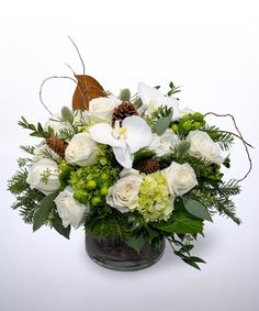 a bouquet of white flowers and greenery in a glass vase on a white background