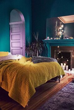 a bedroom with green walls and yellow bedding, candles on the fireplace mantel