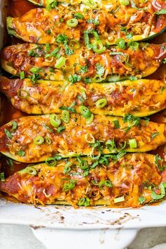 an enchilada casserole in a baking dish with cheese and green onions