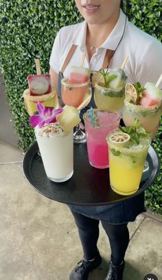 a woman is holding a tray with drinks on it