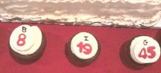 three decorated cookies sitting on top of a red table next to an open cake box