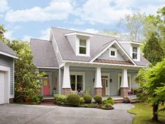 a house with two garages in front of it and landscaping around the driveway area