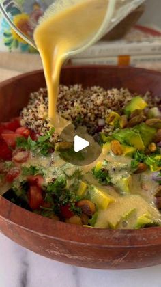 someone pouring dressing into a salad in a bowl