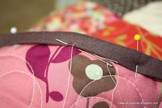 a close up of a pink and brown flowered pillow with pins in the center