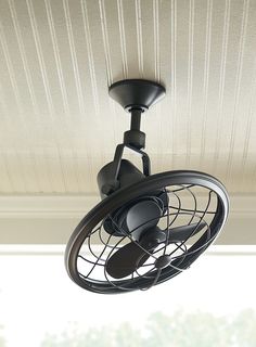 a black ceiling fan sitting on top of a window sill