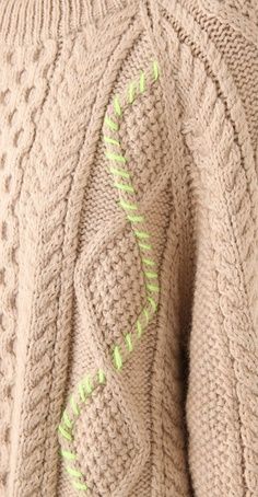 the back of a woman's sweater with green stitching