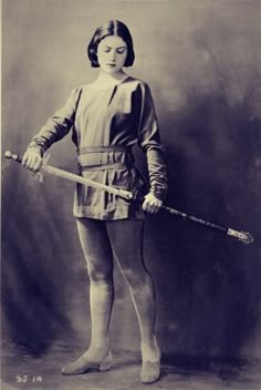 an old black and white photo of a woman in tights holding a baseball bat