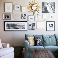 a living room filled with lots of framed pictures on the wall next to a couch