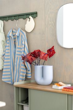 a blue and white vase with red flowers in it on a table next to a mirror