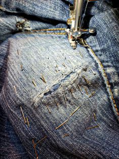 the sewing machine is stitching holes in jeans