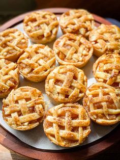 many small pies are on a wooden platter