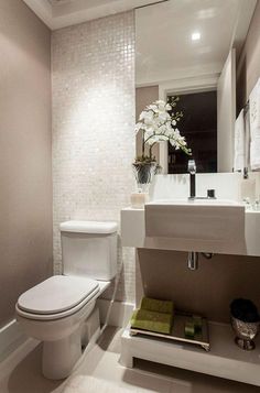 a white toilet sitting next to a sink in a bathroom under a mirror above it