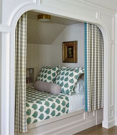 a bed sitting in the corner of a room under a window with curtains on it