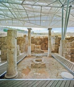 the interior of an ancient building with columns and stone flooring, under a covered area