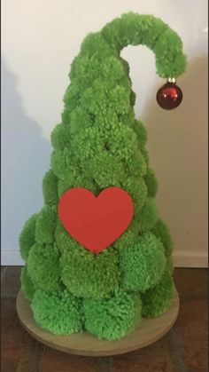 a green christmas tree with a red heart on it's head and decorations around its neck