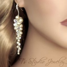 a close up of a woman's face wearing earrings with pearls and crystals on them