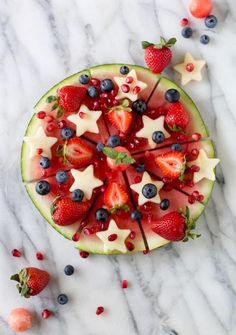 a watermelon topped with strawberries, blueberries and star shaped cutouts