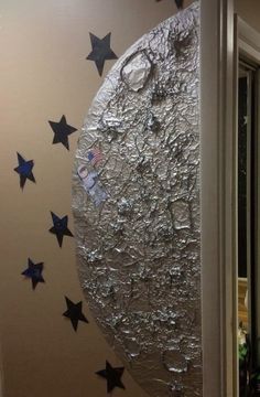 the moon is made out of tin foil and stars are on the wall behind it