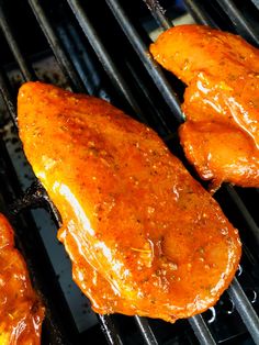 three pieces of chicken cooking on a grill