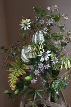 an arrangement of flowers and plants on a wooden stand