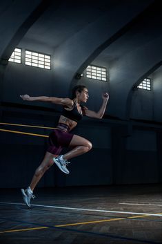 a woman is jumping in the air with her arms outstretched and legs spread out, while wearing running shoes