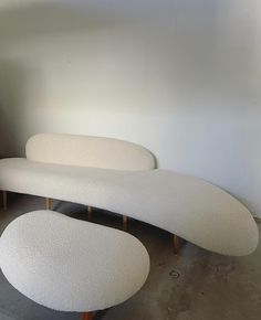 two white couches sitting next to each other on top of a cement floor in a room