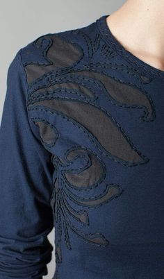 a woman wearing a blue top with an embellishment on it