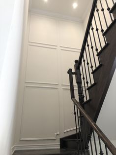 an empty staircase with white walls and black railings