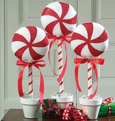 three peppermink lollipops in flower pots on a table with presents