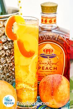 an orange slice is on the rim of a tall glass next to two peaches and a bottle of booze