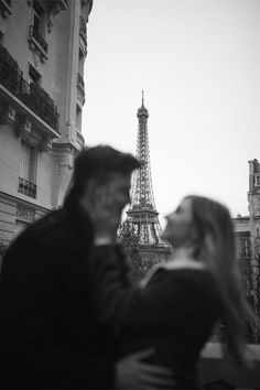 a man and woman standing next to each other in front of the eiffel tower