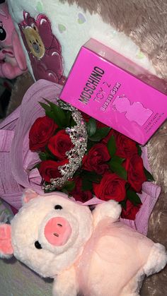 a teddy bear with roses and a tiara next to a pink card box on a bed