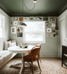 a dining room with a table, chairs and pictures on the wall above it's windows