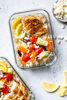 two glass containers filled with rice, chicken and veggies next to lemon wedges