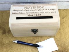 a small wooden box with a pen and note attached to it sitting on a table