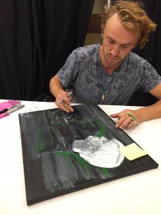 a man sitting at a table with a painting on it