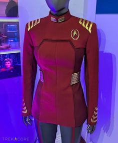 a woman's red star trek uniform on display in a room with purple lighting