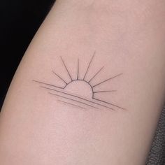 a small sun tattoo on the back of a woman's arm, with lines running through it