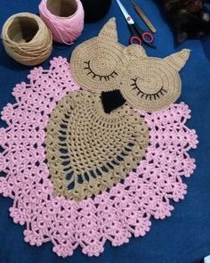 crocheted doily with an owl laying on it next to yarn and scissors