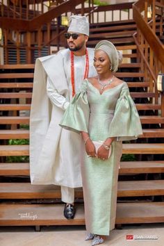 a man and woman dressed in traditional african attire standing next to each other on stairs