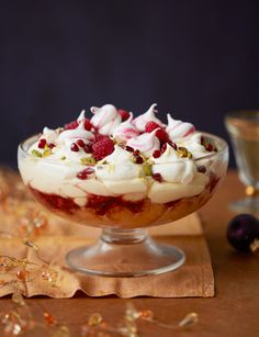 a dessert dish with whipped cream, raspberries and pistachio on top