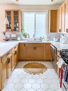 a kitchen with wooden cabinets and white tile flooring on the walls, along with an area rug that looks like hexagonal tiles