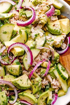 a white bowl filled with cucumber, onions and chicken salad