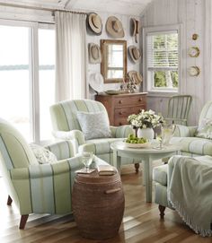 a living room filled with lots of furniture next to a wooden floor covered in white walls