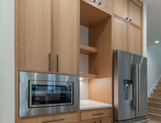 a stainless steel refrigerator freezer sitting in a kitchen next to wooden cabinets and stairs