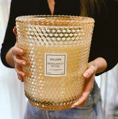 a woman holding a large glass vase in her hands, with a label on it