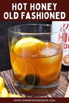 an old fashioned drink in a glass with lemons on the side